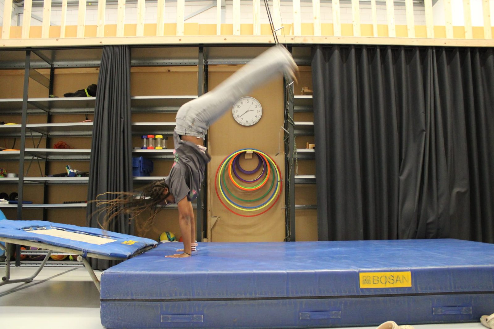 Kind doet een handstand op een dikke mat in een gymzaal